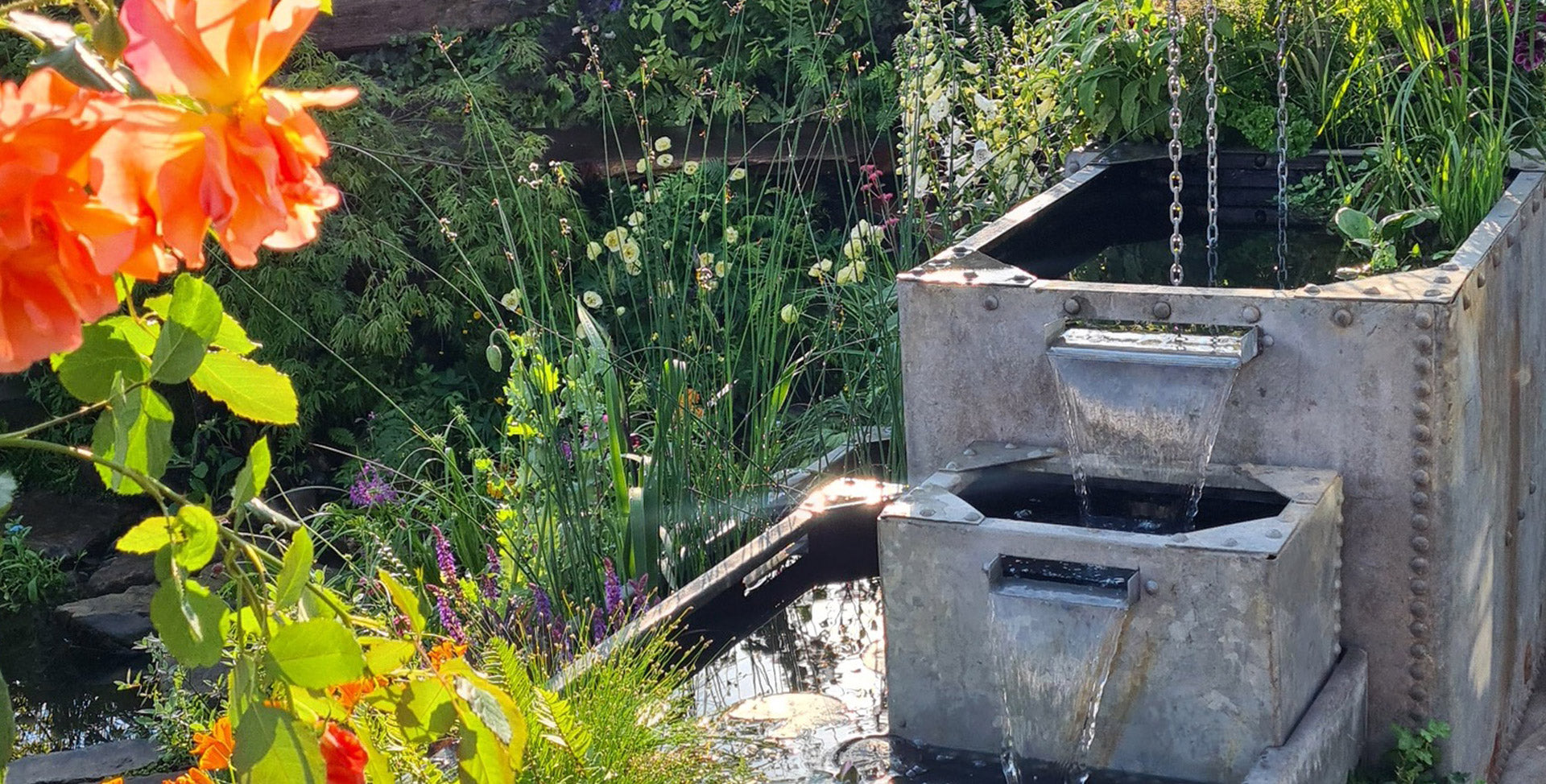 Garden scene with a stone water feature and colorful flowers.